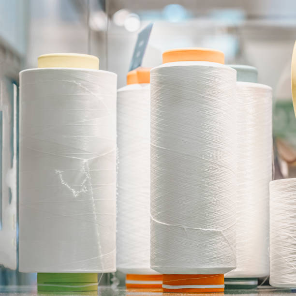 Closeup of several spools of white thread for sewing textiles. Selective focus