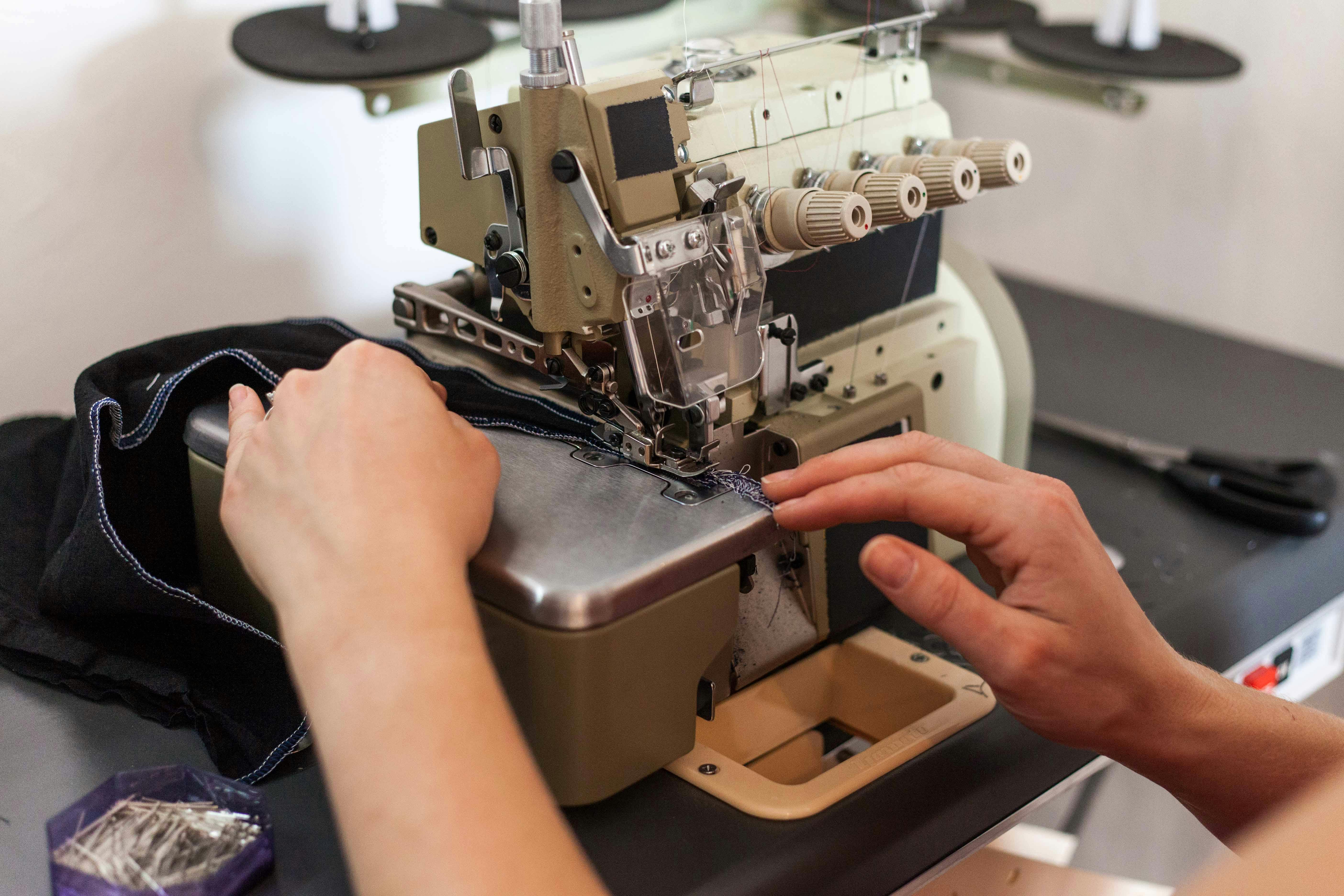 pexels-photo-7998337-7998337 Close-up of hands sewing fabric with a professional sewing machine in a fashion studio.
